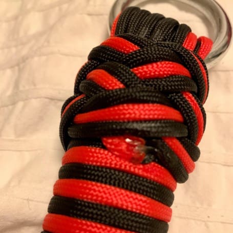 Close-up of the finished braided knot at the end of the handle, just below the metal ring