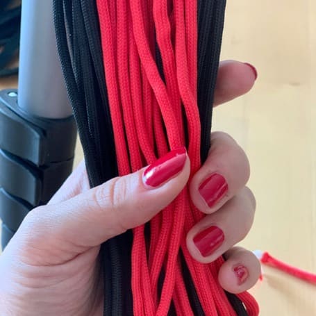 A hand holding together the cut bundle of black and red paracord strands