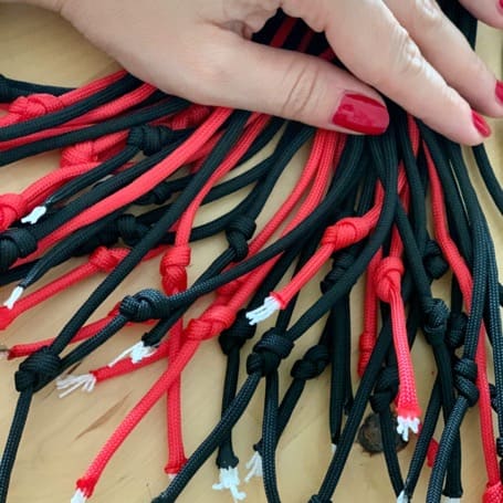 The ends of the black and red paracord strands knotted individually and fanned out on the table