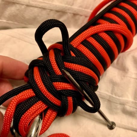 The black and red paracord weave being tightened loop by loop with a needle